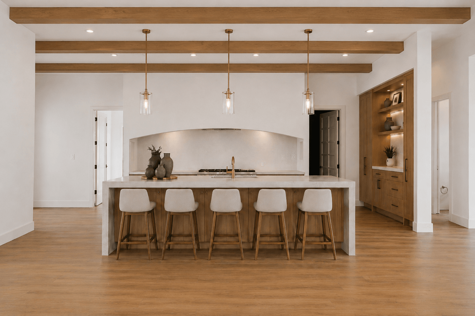 The Mountain View Estate kitchen — island with pendant lights, exposed timber beams, alcove range, and bar seating